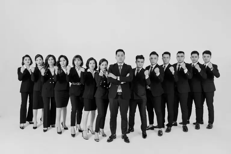 Group of professionals in business attire posing confidently in a studio setting.