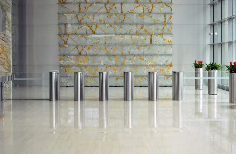 A sleek corporate lobby featuring marble walls, metal dividers, and glass windows for a sophisticated design.