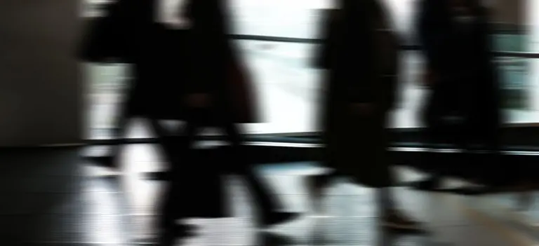 Abstract blurred motion of people walking indoors, depicting urban life and busy routines.