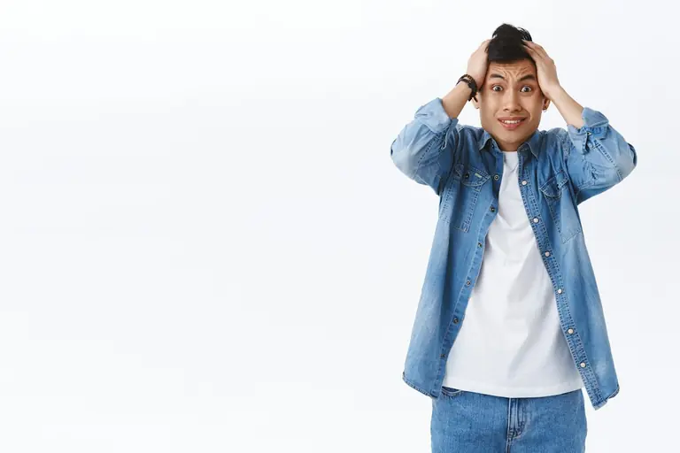 a young man is holding his head with his hands
